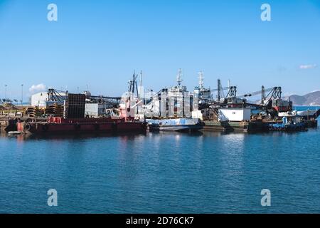 Industrial ships and boats moored in old harbor of Drapetsona Piraeus Greece, blue sky and sea, sunny day. Stock Photo