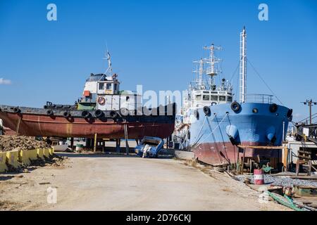 Old industrial ship boat in dry dock for repair, harbor of Drapetsona Piraeus Greece, blue sky, sunny day. Stock Photo