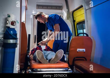 Medical student having an exam, giving an oxygen mask to his patient in an ambulance car. Stock Photo