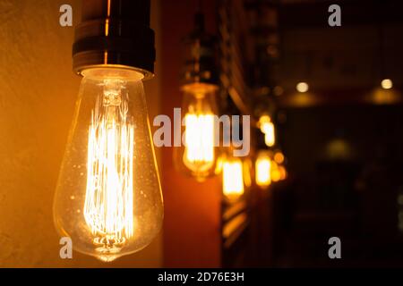 Vintage light bulbs. Lighting decor concept. Golden shining antique Edison style bulbs in the dark. Blur background of retro lights Stock Photo