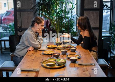 Two girlfriends sitting and having some snacks in a cafe. Stock Photo