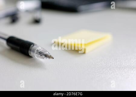 Close up of ballpoint pen and yellow note pad on desk Stock Photo
