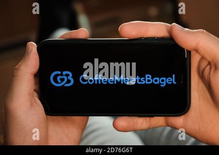 Coffee meets bagel black logo on the screen of mobile phone in mans hand. Application for dating and acquaintance. Man is laying on the sofa and Stock Photo