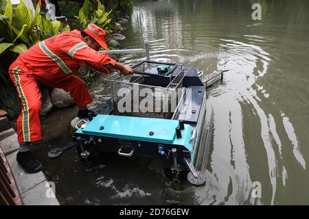 (201021) -- HANGZHOU, Oct. 21, 2020 (Xinhua) -- A sanitation worker collects wastes from an unmanned patrolling and waste collecting machine by a river in Hangzhou, east China's Zhejiang Province, Oct. 21, 2020. A series of high-tech measures were applied to improve the river ecosystem in Hangzhou, including unmanned boats patrolling, automatic watercourse waste cleaning system, artificial intelligence (AI) monitoring system, etc. (Xinhua/Xu Yu) Stock Photo