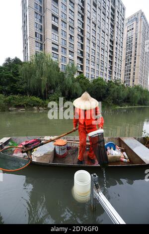 (201021) -- HANGZHOU, Oct. 21, 2020 (Xinhua) -- A sanitation worker collects wastes from an automatic cleaning machine in a river in Hangzhou, east China's Zhejiang Province, Oct. 21, 2020. A series of high-tech measures were applied to improve the river ecosystem in Hangzhou, including unmanned boats patrolling, automatic watercourse waste cleaning system, artificial intelligence (AI) monitoring system, etc. (Xinhua/Xu Yu) Stock Photo