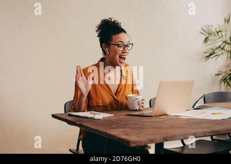 Young woman greeting colleagues on a video call. business woman on a video conference call working from home. Stock Photo