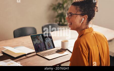businesswoman laughing during a video call with team. Female working from home having video conference with colleagues. Stock Photo