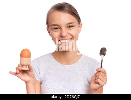 Portrait of beautiful young teen girl, holding boiled egg and spoon for breakfast, isolated on white background Stock Photo