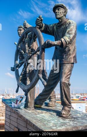 'Man & Boy' is a cast bronze statue by Elisabeth Hadley situated on King's Quay at the harbour in Brixham, South Devon. The statue is dedicated to liv Stock Photo