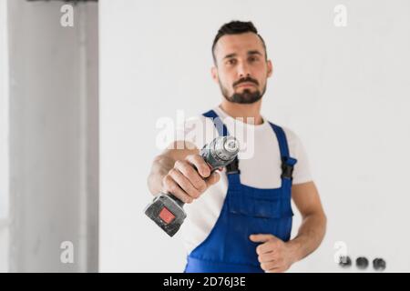 Craftsman holds a drill in his hand and looks at the camera Stock Photo