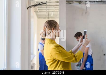 Female inspector makes a photo on the phone of the work of builders Stock Photo