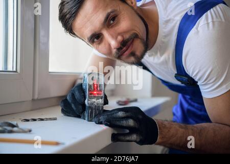 The fitter measures the distance from the window with a level Stock Photo