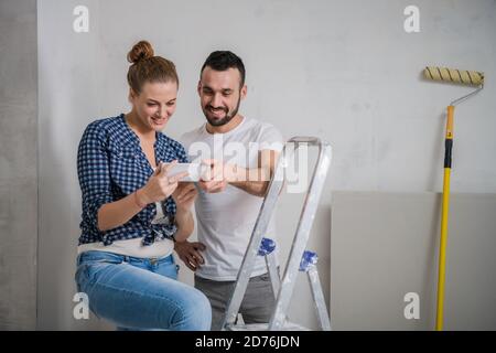 Family couple sitting on a stepladder and looking at photos on the phone Stock Photo