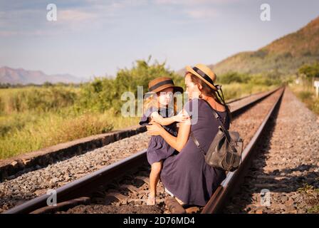 Mother with the daughter go on rails, back to a camera, on nature, in the summer Stock Photo