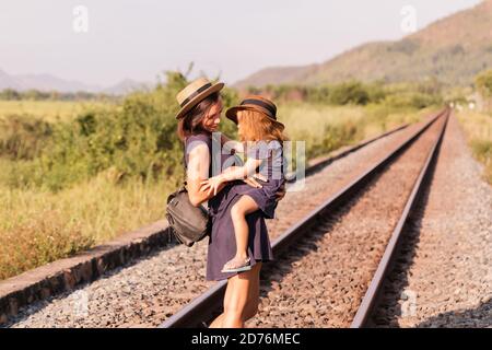 Mother with the daughter go on rails, back to a camera, on nature, in the summer Stock Photo