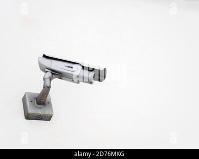 Silver CCTV camera angled to the side on a white wall Stock Photo