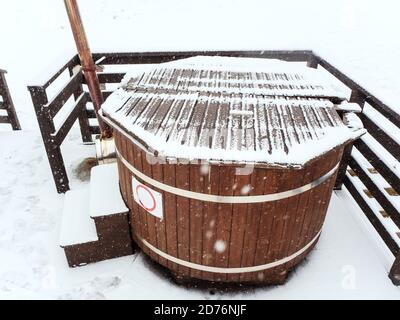 Wooden furaco hot tub stands on the terrace on a snowy winter day Stock Photo