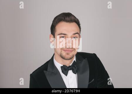 Studio portrait of a young caucasian man in a tuxedo, looking at the camera, against plain studio background Stock Photo