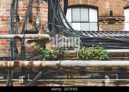Rusty pipes, cabling and weeds on the roof of an old factory Stock Photo