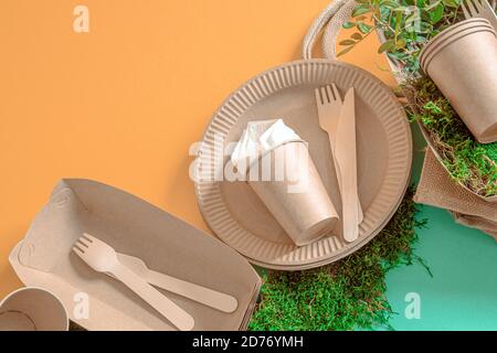 ECO craft paper tableware. Paper cups, plates, bag, fast food containers and wooden Cutlery with cornstarch on a colored orange-blue background. Stock Photo