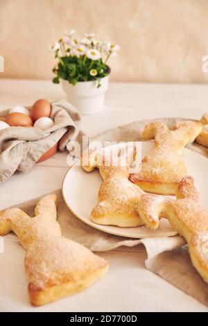 Easter bunny biscuits, Easter eggs and potted flowers on a white wooden table Stock Photo