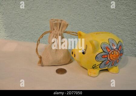 Bag full of money and yellow Piggy Bank over blue background. Coin on the desk Stock Photo