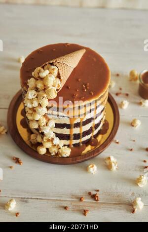 Delicious cake topped with caramel cream and a cone filled with popcorn on it Stock Photo