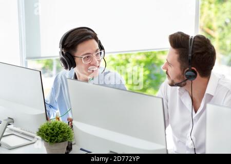 Male customer support service operators with headsets talking at light office Stock Photo