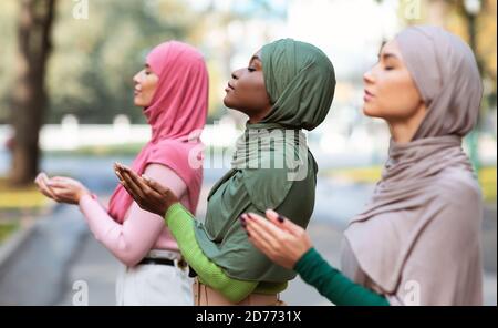 Three Islamic Ladies Praying Standing Together Outside Wearing Traditional Hijab Stock Photo