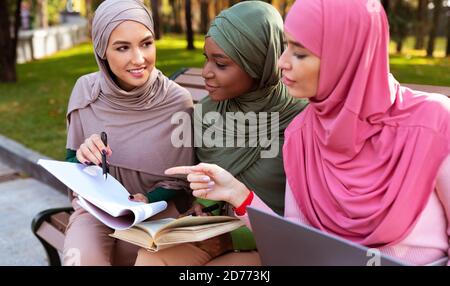 Three Muslim Ladies Learning Reading Books Sitting In Park Outdoors Stock Photo