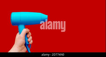 Blue hair dryer on a red background with copy space. Modern equipment for a hairdresser Stock Photo