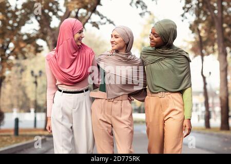 Three Muslim Women Wearing Hijab And Modern Clothes Walking Outside Stock Photo