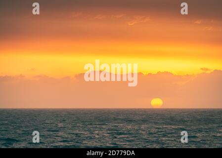 Big yellow sun falling behind the sea at Christies Beach during sunset time, South Australia Stock Photo