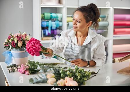 Enthusiastic female florist making a bouquet of pretty flowers Stock Photo