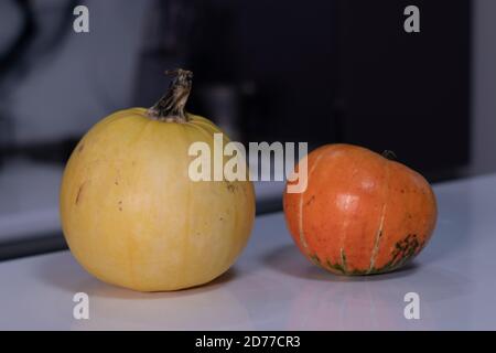 two pumpkins on white table in gray kitchen. halloween concept. Stock Photo