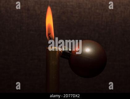 Gold color shiny candle fire and orange flame, decoration ball, on brown background. Creative christmas tree. Stock Photo