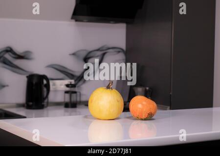 two pumpkins on white table in gray kitchen. halloween concept. Stock Photo