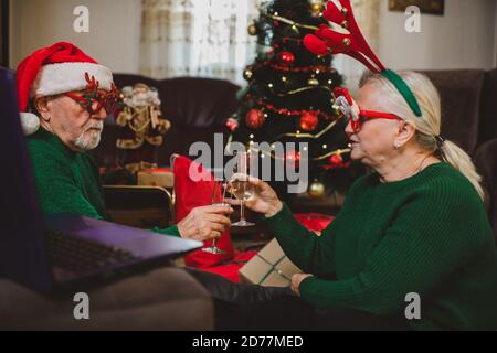 Senior couple at home having a Christmas celebration on a video call Stock Photo