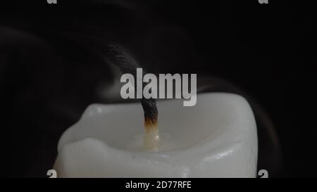 Image of smouldering white candle on black background Stock Photo