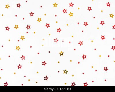 Christmas confetti stars composition. Flat lay of gold and red stars on a white background. Top view. Stock Photo