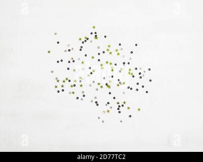 Multicolored sequins and green stars on a textured white background. Festive concept. Perfect background for your design. Stock Photo