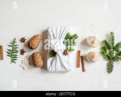 Flat lay fabric wrapped gift with fir tree branch and nature decor. Christmas reusable sustainable gift wrapping alternative. Zero waste concept. Copy Stock Photo