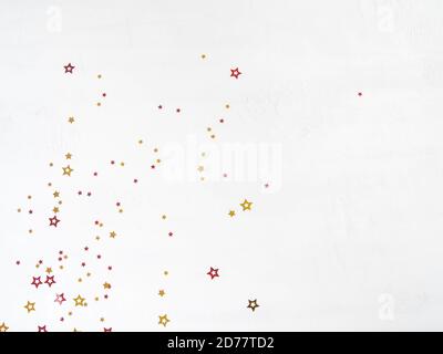 Christmas confetti stars composition. Flat lay of gold and red stars on a white background. Top view. Copy space Stock Photo