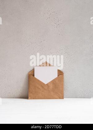 Open kraft envelope and empty postcard near the gray wall, front view. Copy space Stock Photo