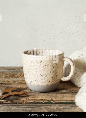 Two-tone mottled cup with a drink and a knitted blanket on an old wooden table. Copy space Stock Photo