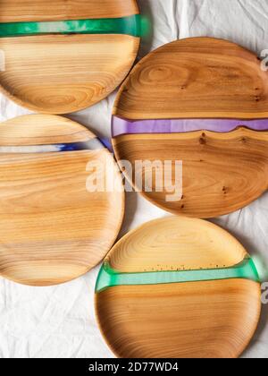 Various round wooden craft trays with resin inserts on a white textile background. Top view. Copy space Stock Photo