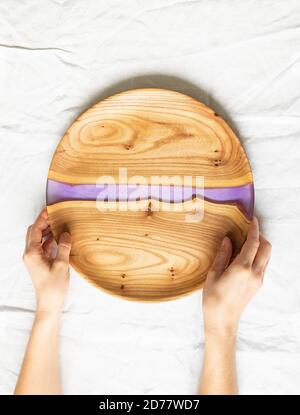 Female hands holding round wooden craft trays with a green resin