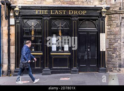 Edinburgh, United Kingdom. 21 October, 2020 Pictured: Scottish First Minister Nicola Sturgeon has ordered pubs in the Central Belt to remain closed until new 5 tier restrictions are introduced on 2 November 2020. A passer-by walks past The Last Drop pub in Edinburgh’s Grassmarket. Credit: Rich Dyson/Alamy Live News Stock Photo