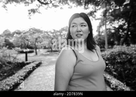 Beautiful overweight Asian woman relaxing at the park in the city Stock Photo