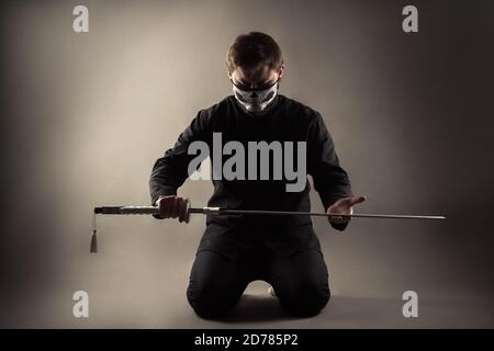brutal man with katana on knees Stock Photo